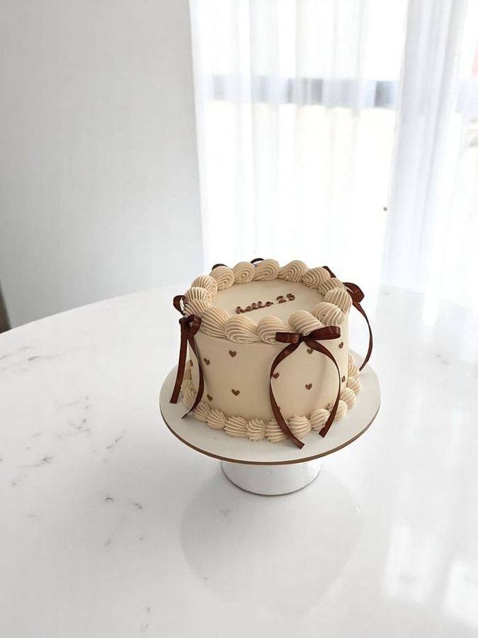 A cream birthday cake tied with brown bows